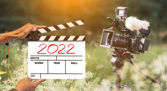 The year 2022. film crew holding a film slate and a camera filming a movie in the outdoor background.Happy new years film industry.