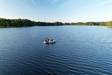 Fishermen in a boat fishing in the lake. Fishing for river fish from a motor boat using a fishing rod or spinning rod. Sports fishing on the water. Rest in the wild