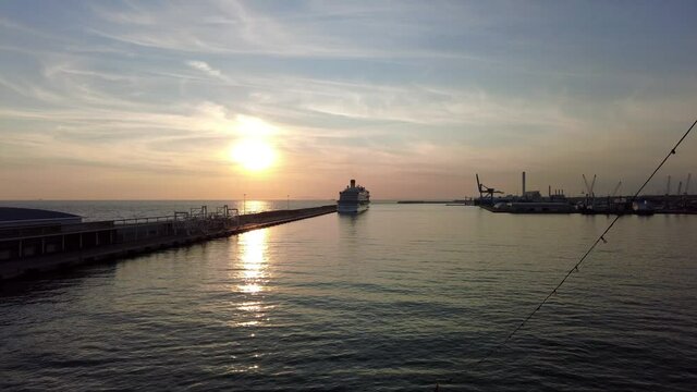 On board ship at sunset with fantastic sun and sky a panning harbor skyline with facilities boat and cruise ship