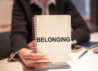 Business woman holds a notebook with the text BELONGING.