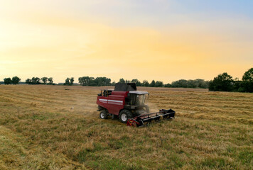 Obraz premium Combine harvester working in wheat field. Top view of the harvesting machine during cutting crop in a farmland. Aerial view of Combines during grain harvesting. Flour and bread production.
