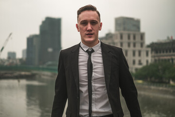 Portrait of attractive caucasian young businessman in black formal suit outdoors in the big city. Looking at camera with copy space. Serious man.