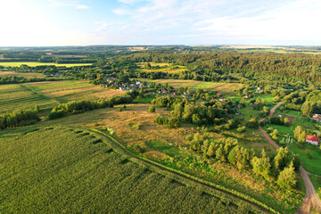 Top view of the village with wooden houses in wild among the forest and field. Aerial view of country house in countryside. Roofs of suburban homes. Housing outside the city in an ecological area.