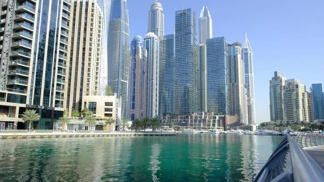 Dubai, UAE, 15.02.2021: Dubai Marina skyline with Marina Canal, modern skyscrapers, luxury hotels. A sunny day in the bay, calm waves reflecting the sunlight