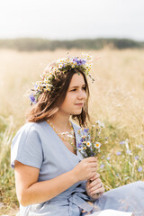 Cute smiling little girl with flower wreath on the meadow. Portrait of adorable small kid outdoors.