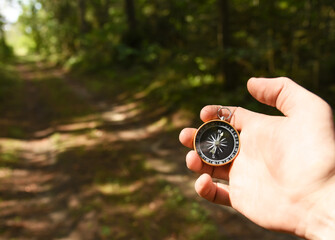 Compass in hand at forest. Tourist compass for orientation on the terrain. Magnetic declination...