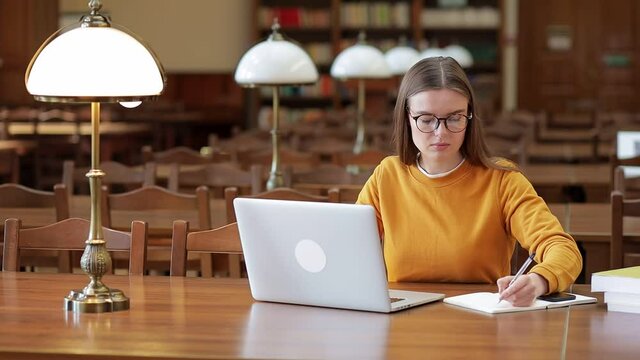University library: a gifted girl uses a laptop, does her homework after school.