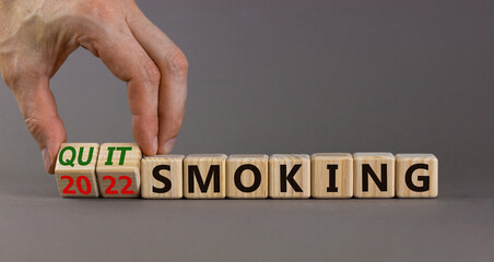 Quit smoking 2022 new years resolution symbol. Businessman turns wooden cubes with words '2022 quit smoking'. Beautiful grey background, copy space. Healthy lifestyle and 2022 quit smoking concept.