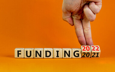 2022 funding and new year symbol. Businessman turns wooden cubes, changes words funding 2021 to funding 2022. Beautiful orange background, copy space. Business, 2022 funding and new year concept.