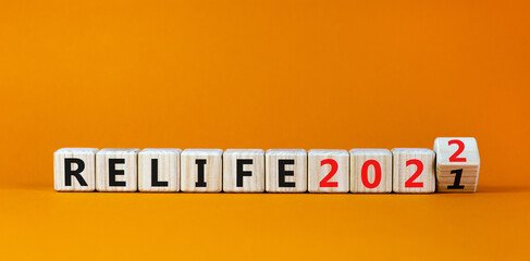 Planning 2022 relife new year symbol. Turned a wooden cube and changed words 'relife 2021' to 'relife 2022'. Beautiful orange background, copy space. Business, 2022 relife new year concept.