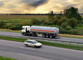 Isothermal Tank truck driving on highway. Oil and Gas Transportation and Logistics. Metal chrome cistern tanker with petrochemicals products. Liquid Chemical Freight. Out of focus
