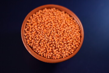 Some lentil grains on a clay bowl with colorful background 