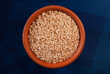 Some lentil grains on a clay bowl with colorful background 