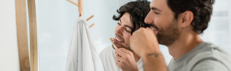 happy gay couple brushing teeth in bathroom, banner