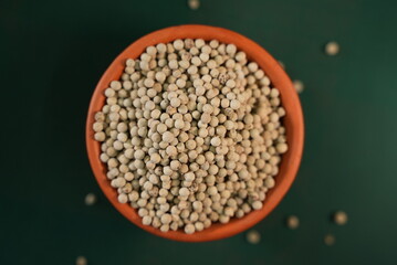 Some lentil grains on a clay bowl with colorful background 
