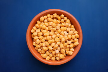 Some lentil grains on a clay bowl with colorful background 