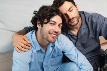 pleased young gay couple hugging in bedroom