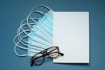 blue protective masks, white rectangular card with space for text, brown glasses, photo from above