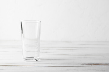 Empty kitchen glass tumbler on white wooden background.