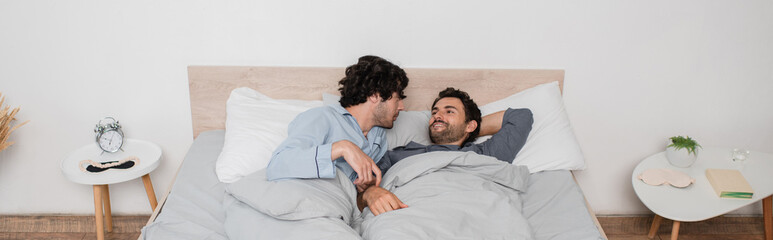 gay couple lying on bed in morning, banner