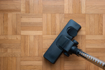 Vacuum cleaner attachment on wooden floor tiles inside room, no people, top view