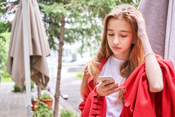 Fototapeta premium Pretty girl outdoors. Caucasian real people using mobile phone. Single female person. Staycation ecology concept. Positive attractive human portrait