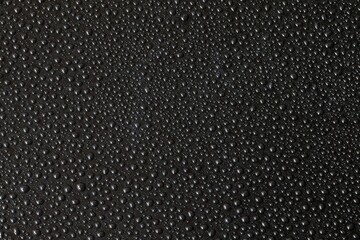 Background with black droplets. An enormous number of water droplets on black surface. Top view