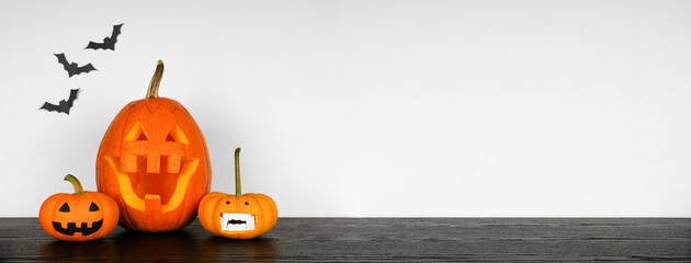 Halloween display with jack o lanterns and pumpkins on a black shelf against a white wall with...