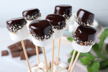 Delicious marshmallows covered with chocolate on sticks, closeup
