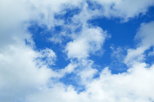 Beautiful white clouds against a blue sky, copy space. Blue sky with clouds, free space. Clouds at the top right of the frame. Texture. The background. The sun shines through the clouds.