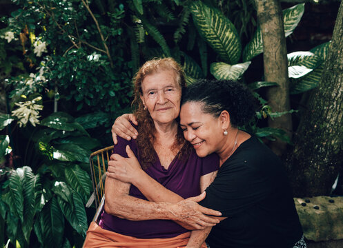 latin woman with curly hair hugging her old mother while smiling
