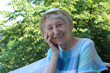 Positive senior woman watering decorative plants on balcony