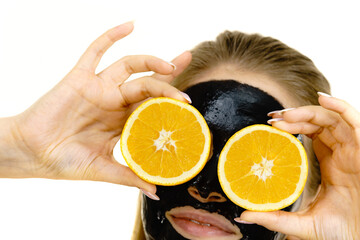 Girl black carbo mask on face holds orange fruit