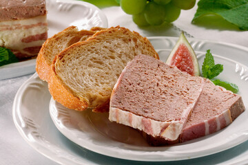 Patê de Foie Gras em fatia junto ao pão italiano no prato em mesa decorada, clouse up.
