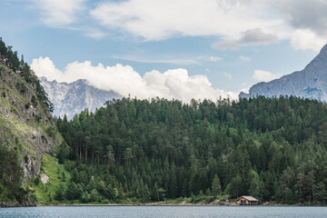 Blindsee lake shore with a boat shed with forest and mountains in a background