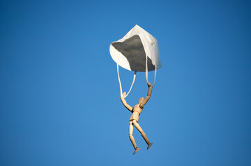 Wooden figure flying with respirator mask as parachute, destined to prevent the spread of the coronavirus, COVID-19.