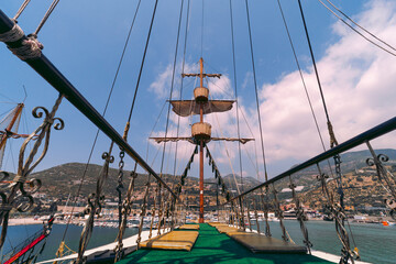 Old pirate ship on the water of Mediteranean sea. Tourist entertainment, coastal tour. Summer sunny day. Mountain shore of Alanya. Turkey.