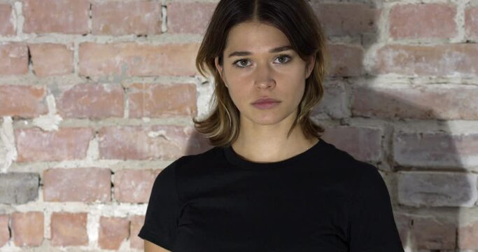 A closeup view of a woman with short hair and a black shirt frowning then smiling in 4k