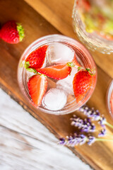Fresh fruit summer drink with strawberry, lime and ice placed on wooden desk