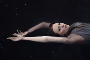 Beautiful woman floating in dark waters