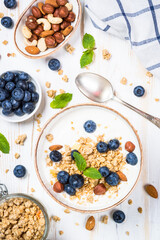 Yogurt granola with fresh blueberries on white wooden table. Top view with copy space. Healthy food, snack or breakfast.