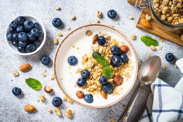 Yogurt with granola and fresh berries at stone table. Top view with copy space. Healthy food, snack or breakfast.
