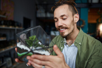Cheerful young man holding geometric glass terrarium