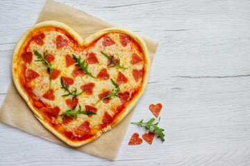 Heart shaped Italian pizza with pepperoni,arugula,pizza sauce and mozzella cheeses on parchment...