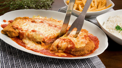 Filé Mignon a parmegiana, com queijo mussarela derretido e molho de tomate em fundo de mesa.