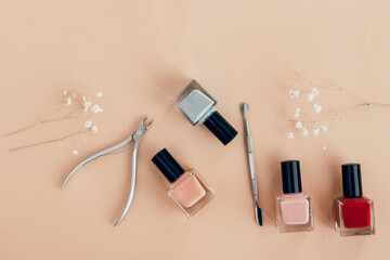 nail polish and manicure tools on beige background flat lay