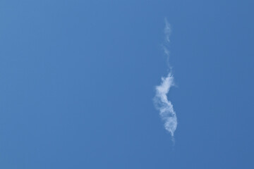 white clouds form vertical lines The background is a bright blue sky.