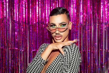 Closeup portrait of drag queen diva with fuchsia glitter background