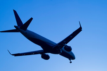 silhouette of a passenger plane seen from below over blue sky background