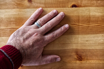 Top view of a man's hand wearing a silver ring place on a wooden table